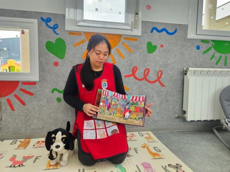 Anselma, sitting on the classroom mat, shows a pop-up book; Pepo sits beside her